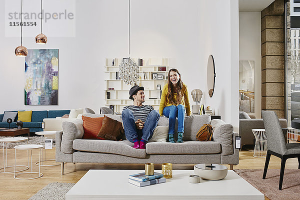 Paar im modernen Möbelhaus auf der Couch sitzend  lachend
