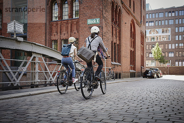 Deutschland  Hamburg  Rückansicht des Ehepaares auf Elektrofahrrädern im Alten Speicherstadtteil