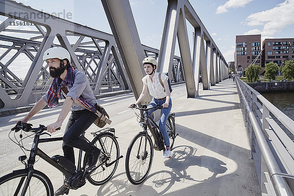 Deutschland  Hamburg  Paar mit Elektrofahrrädern auf einer Brücke