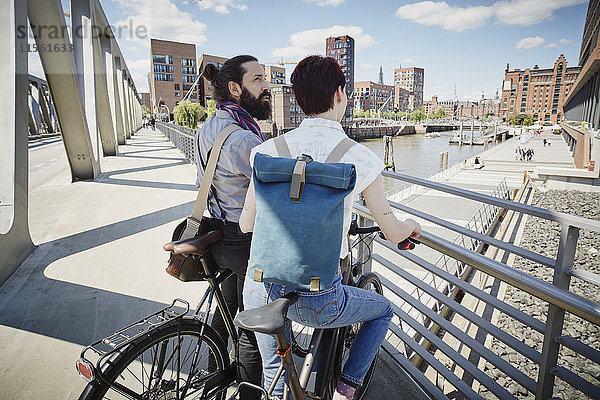 Deutschland  Hamburg  Paar mit Elektrofahrrädern auf einer Brücke
