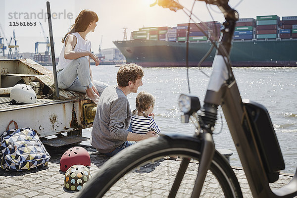 Deutschland  Hamburg  Familie bei einer Radtour an der Elbe beim Beobachten eines Containerschiffes