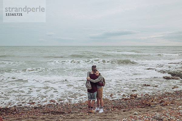 Schwules Paar  das sich am Strand vor dem Meer umarmt