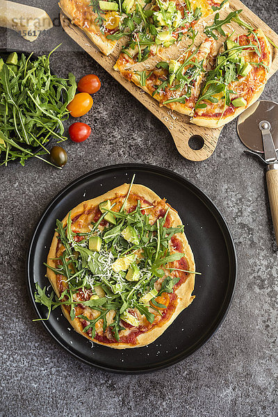 Vegetarische Pizza mit Avocado  Rucola  Tomaten und Parmesan