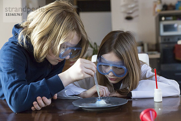 Zwei Kinder mit Schutzbrille und Chemie-Set zu Hause