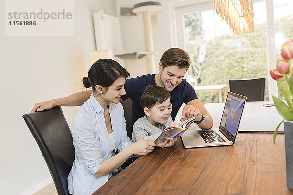 Familie mit Laptop und Reiseführer bei der Urlaubsplanung zu Hause