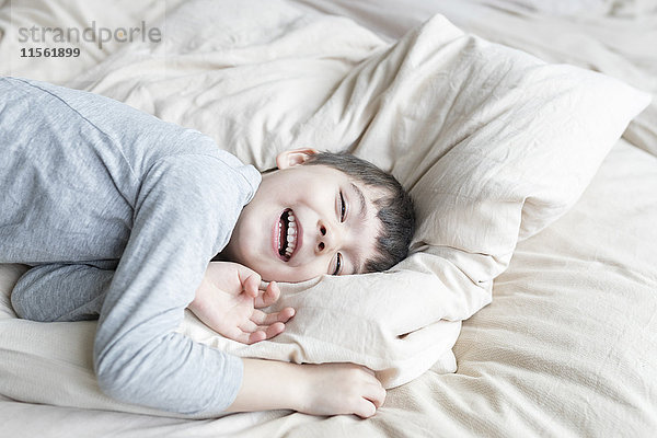 Glücklicher Junge im Bett liegend