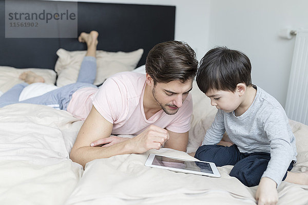 Vater und Sohn schauen auf die Tafel im Bett
