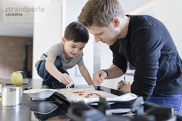 Vater und Sohn kochen gemeinsam Pizza in der Küche