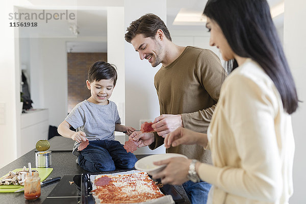 Familie bereitet gemeinsam Pizza in der Küche zu
