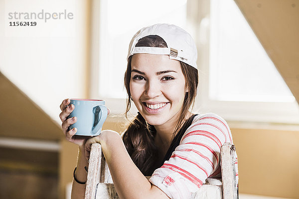 Junge Frau auf der Baustelle mit einer Tasse Kaffee