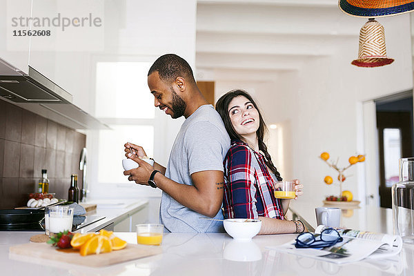 Junges Paar beim Frühstück in der Küche  Rücken an Rücken stehend