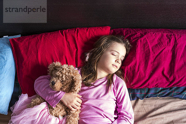 Mädchen mit Teddybär im Bett schlafend
