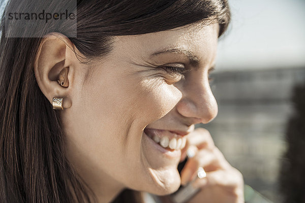 Glückliche junge Frau mit Hörgerät am Telefon
