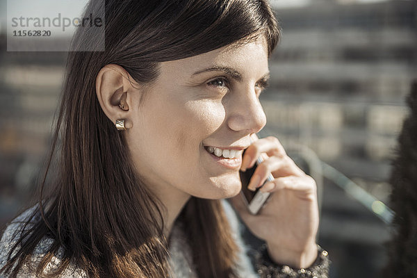 Lächelnde junge Frau mit Hörgerät am Telefon
