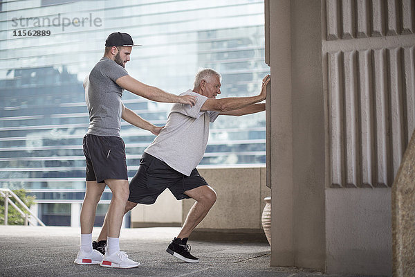 Fitnesstrainer  der den älteren Mann bei einer Stretching-Übung führt.