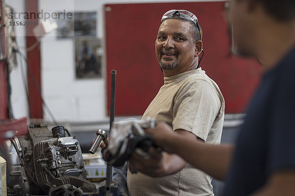 Zwei Mechaniker bei der Arbeit am Motorradmotor in der Werkstatt