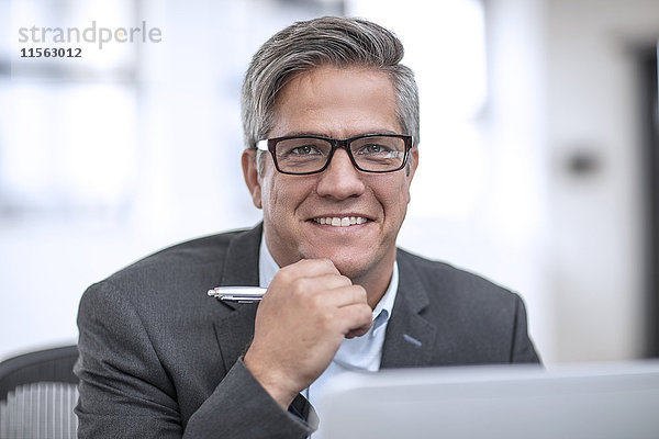 Geschäftsmann mit Brille im Büro sitzend  lächelnd