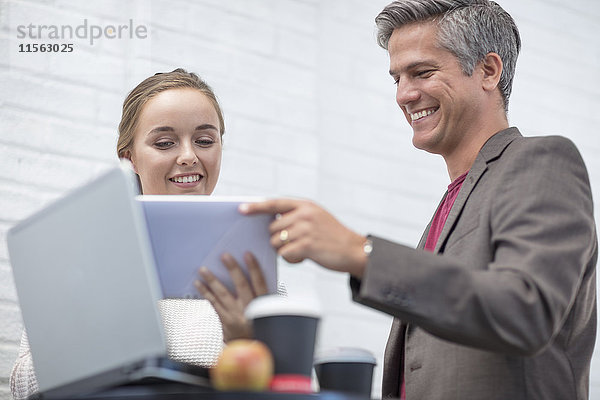 Geschäftsmann und Frau bei einem Treffen mit Blick auf das digitale Tablett