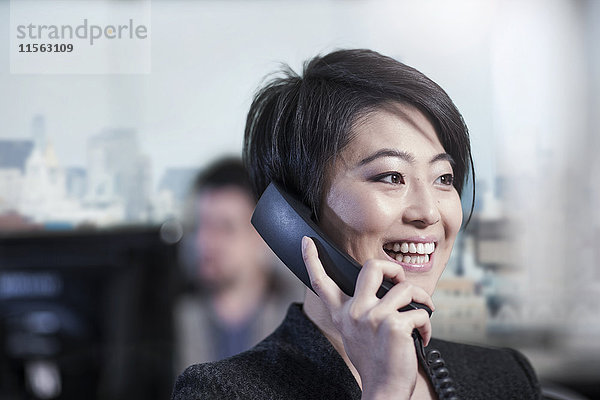 Lächelnde Frau im Büro beim Telefonieren