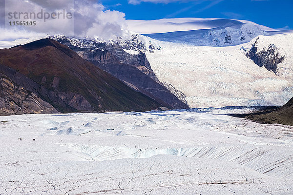 Die Menschen auf dem Root Glacier im Wrangell-St. Elias National Park werden von der umgebenden Landschaft  einschließlich des massiven Stairway Icefall im Hintergrund  in den Schatten gestellt  Süd-Zentral-Alaska  USA