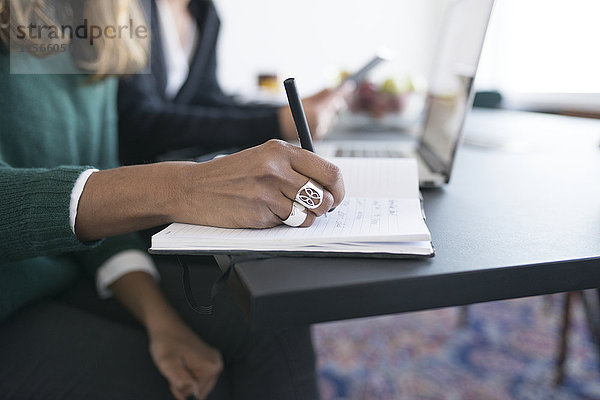 Geschäftsfrau schreibt in Tagebuch im Büro