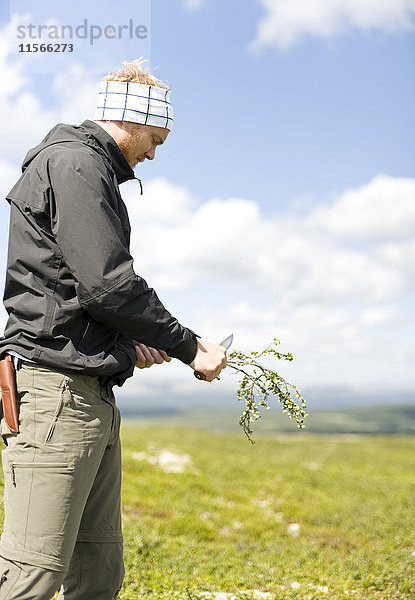 Wanderer schneidet Zweig mit Messer