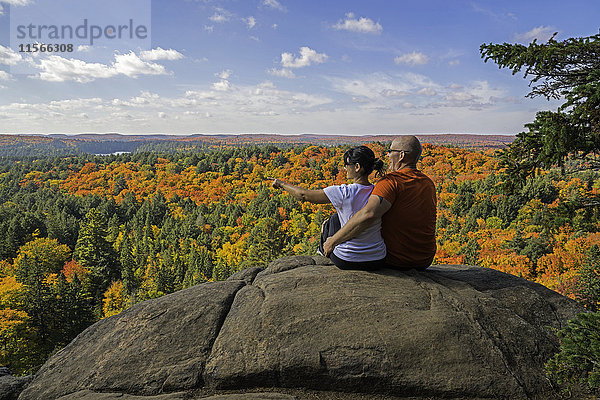 Junges Paar  das auf einer Klippe sitzt und die Herbstfarben des Algonquin Park betrachtet; Ontario  Kanada'.