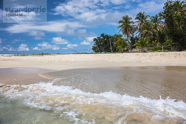 Eine Welle plätschert auf den weißen Sandstrand und den Dschungel im Hintergrund auf der unbewohnten Insel Cayo Zapatilla in Bocas del Toro  Panama.