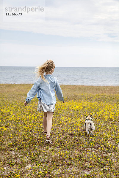 Mädchen geht mit Hund am Meer spazieren