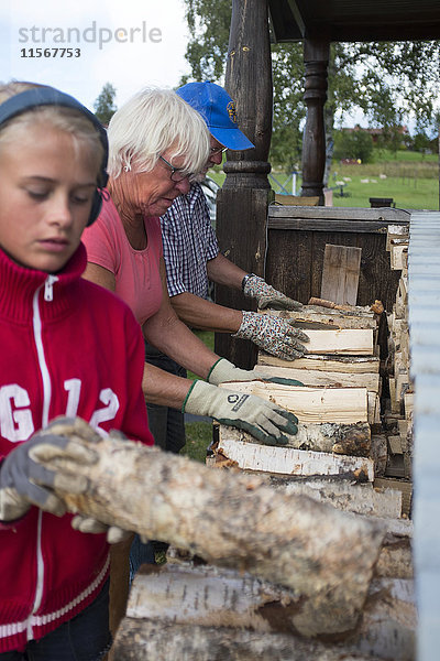 Mädchen und Großeltern lagern Brennholz
