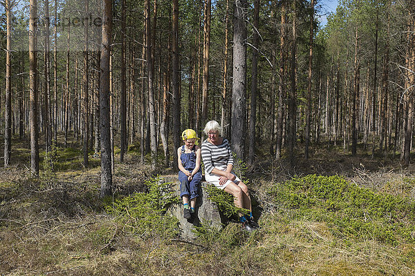 Großmutter mit Enkelin im Wald sitzend