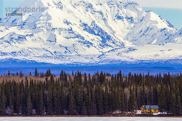 Blick vom Richardson Highway südlich von Glennallen auf ein Blockhaus auf einem zugefrorenen See mit Mount Drum im Hintergrund; Alaska  Vereinigte Staaten von Amerika'.