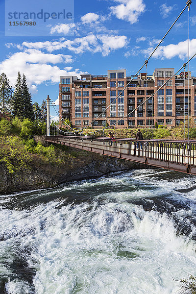 Menschen gehen auf einer Fußgängerbrücke über den Spokane River; Spokane  Washington  Vereinigte Staaten von Amerika'.
