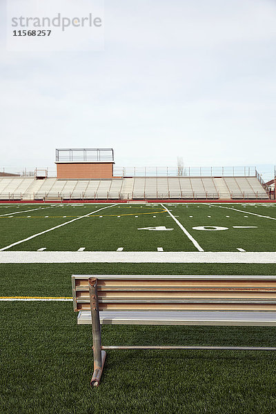American-Football-Feld mit Bank im Vordergrund und leeren Tribünen im Hintergrund