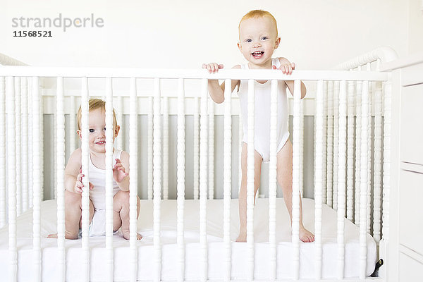 Zwillingsbrüder (12-17 Monate) spielen im Kinderbett
