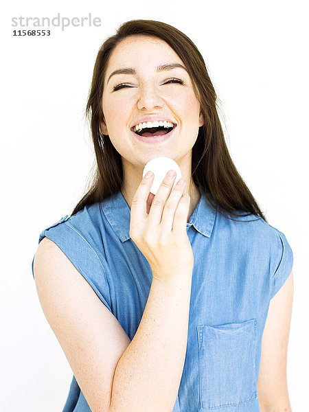 Porträt einer lachenden Frau mit Wattebausch in der Hand