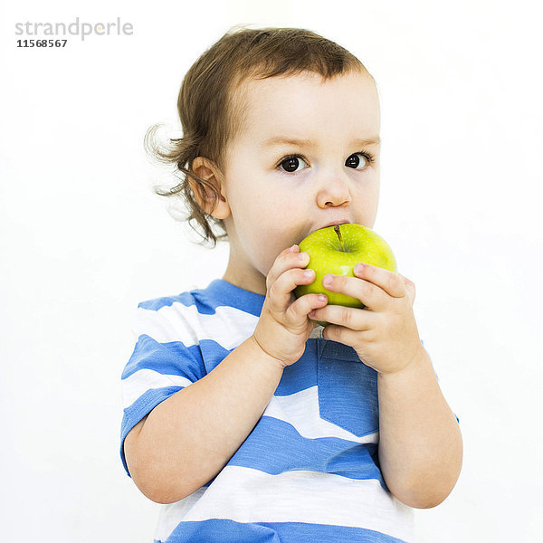 Junge (4-5) mit T-Shirt isst grünen Apfel