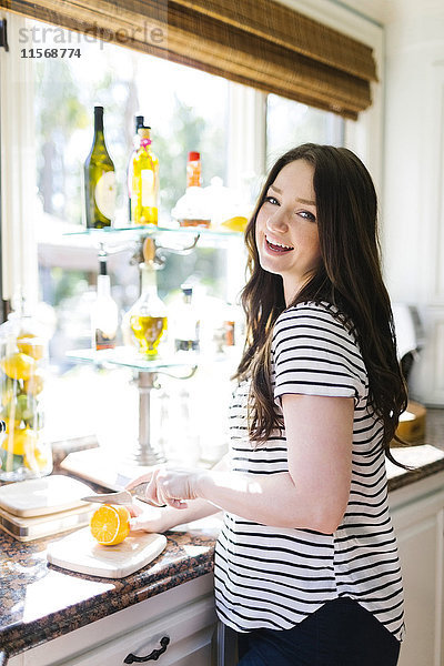 Frau schneidet Zitrone in der Küche