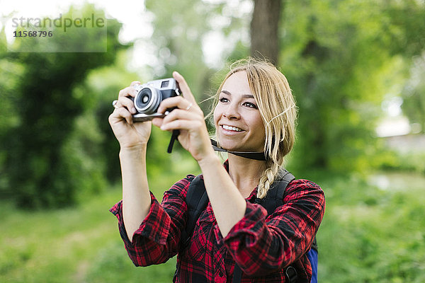 Junge Frau beim Fotografieren im Park