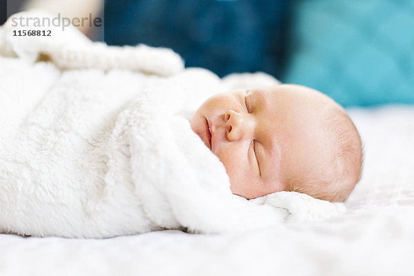 Kleiner Junge (2-5 Monate) schläft in weißer Decke