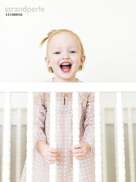 Inhalt kleines Mädchen ( 12-17 Monate) mit offenem Mund im Kinderbett stehend