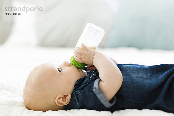 Seitenansicht eines kleinen Jungen (12-17 Monate)  der Milch aus der Flasche trinkt