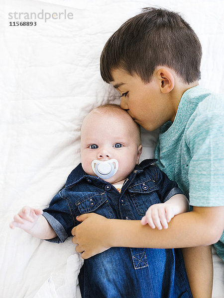 Porträt eines Jungen (8-9)  der seinen jüngeren Bruder (12- 17 Monate) küsst