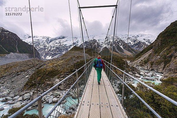 Wanderer geht Hängebrücke über den Fluss Hooker  Hooker Valley  Mount Cook National Park  Canterbury Region  Neuseeland  Ozeanien