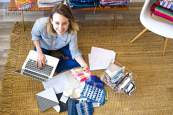 Portrait einer Innenarchitektin mit Laptop auf dem Boden im Einzelhandelsstudio