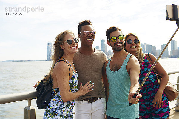 Vier erwachsene Freunde beim Smartphone-Selfie am Wasser mit Skyline  New York  USA