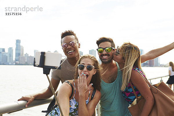 Vier erwachsene Freunde posieren für Smartphone-Selfie am Wasser mit Skyline  New York  USA