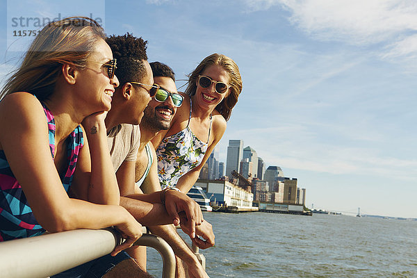 Vier erwachsene Freunde  die von der Uferpromenade des Flusses hinausblicken  New York  USA