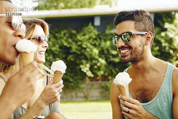 Männliche und weibliche Freunde essen Eistüten im Park