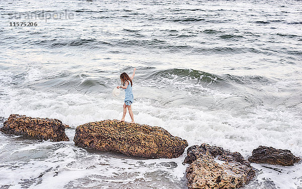 Frau genießt Spaziergang auf Felsen im Meer